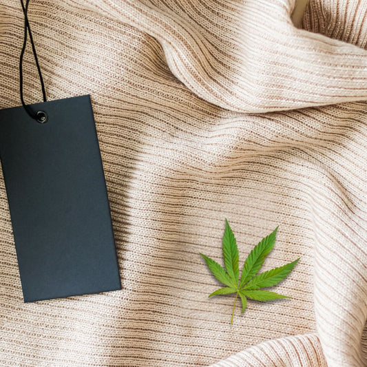A piece of clothing and with a green weed leaf laying on top, along side a black price tag.